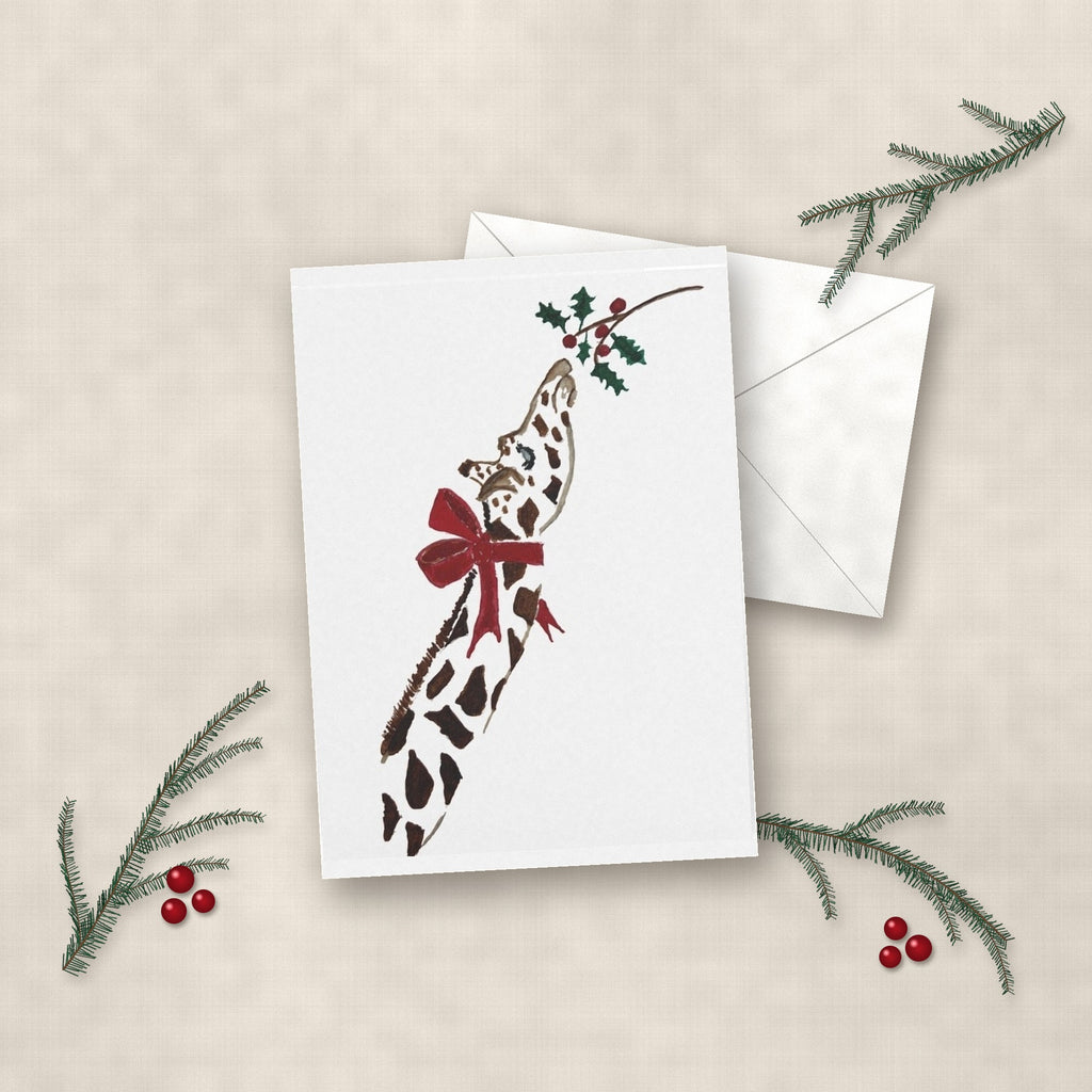 Deck the Halls giraffe watercolor Christmas card on linen with white envelope, pine sprigs and red berries
